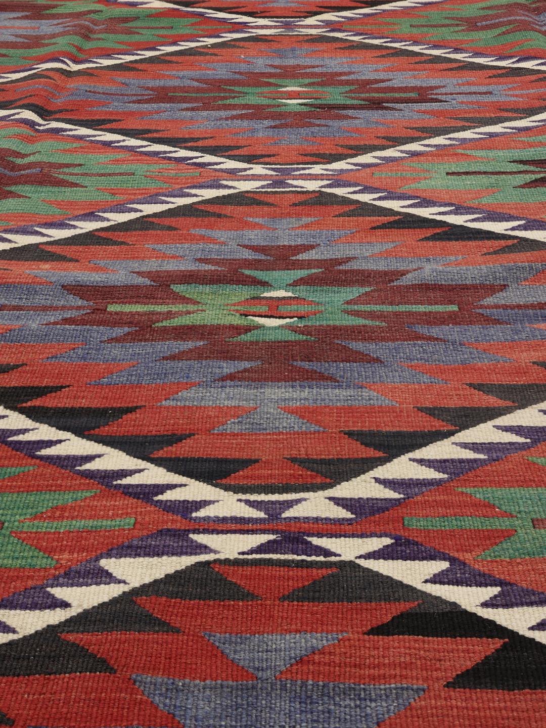 Een kleurrijk vintage Turks Kelim-kleed met geometrische ruitpatronen in rood, groen en blauw.