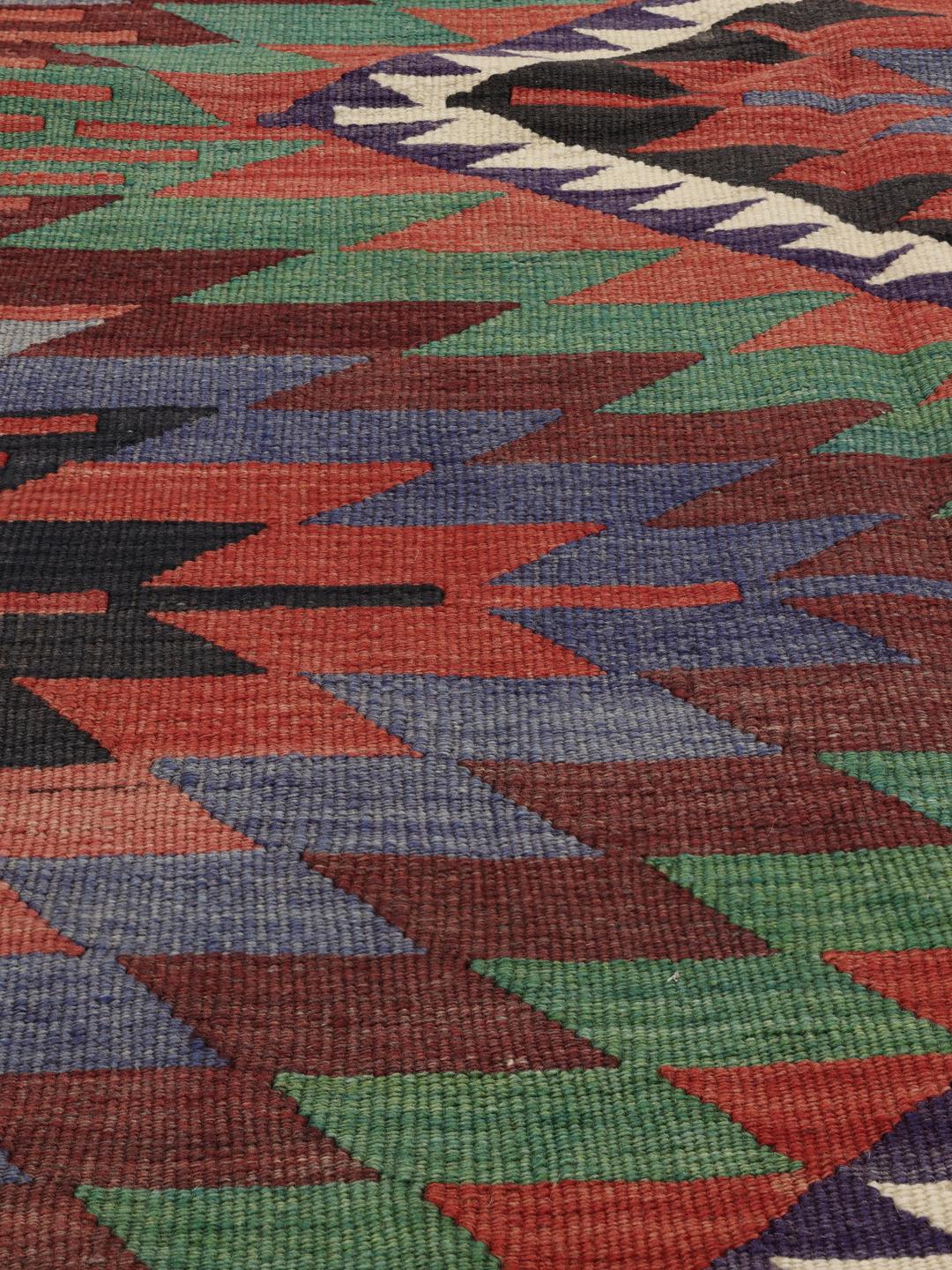 Een kleurrijk vintage Turks Kelim-kleed met geometrische ruitpatronen in rood, groen en blauw.