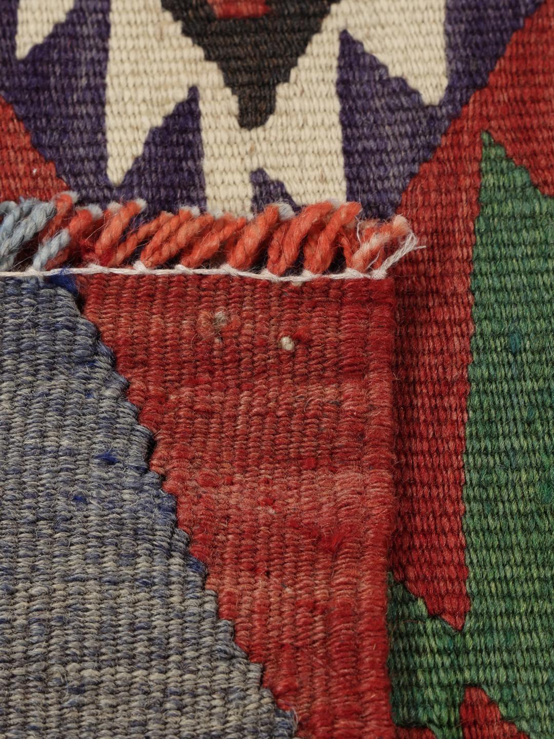 Een kleurrijk vintage Turks Kelim-kleed met geometrische ruitpatronen in rood, groen en blauw.