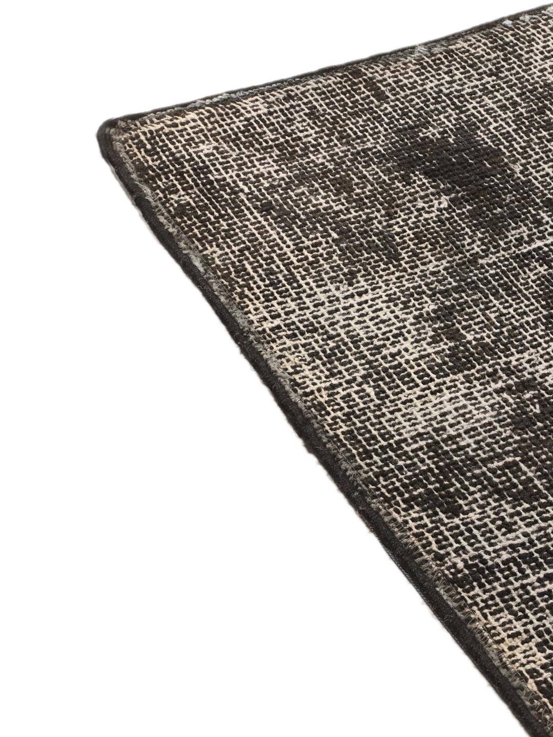 Een groot rechthoekig patchwork vloerkleed uit Turkije met een verweerd zwart en grijs patroon.
