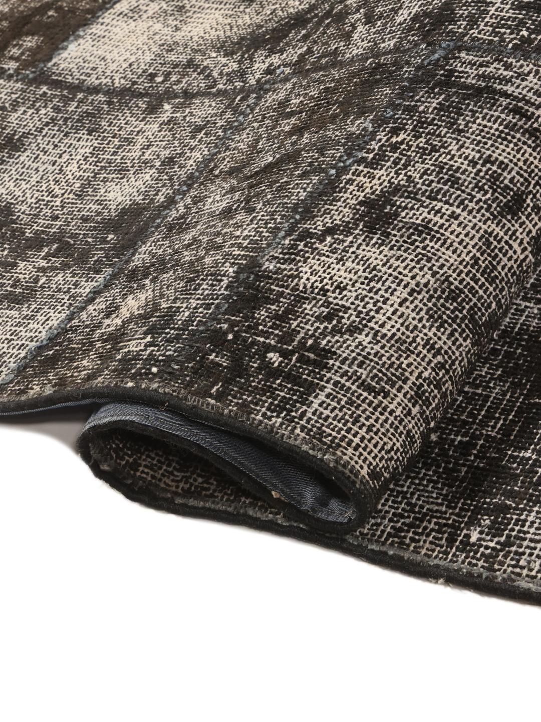 Een groot rechthoekig patchwork vloerkleed uit Turkije met een verweerd zwart en grijs patroon.