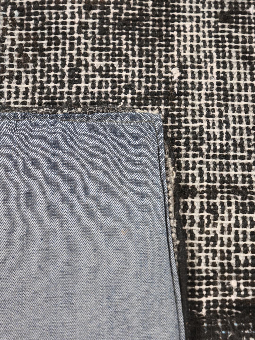 Een groot rechthoekig patchwork vloerkleed uit Turkije met een verweerd zwart en grijs patroon.