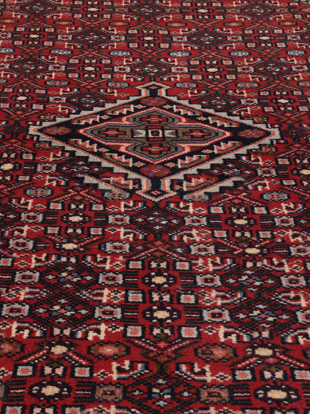 A hand-knotted Hamadan rug from the Middle East featuring a vibrant red and dark blue geometric pattern.
