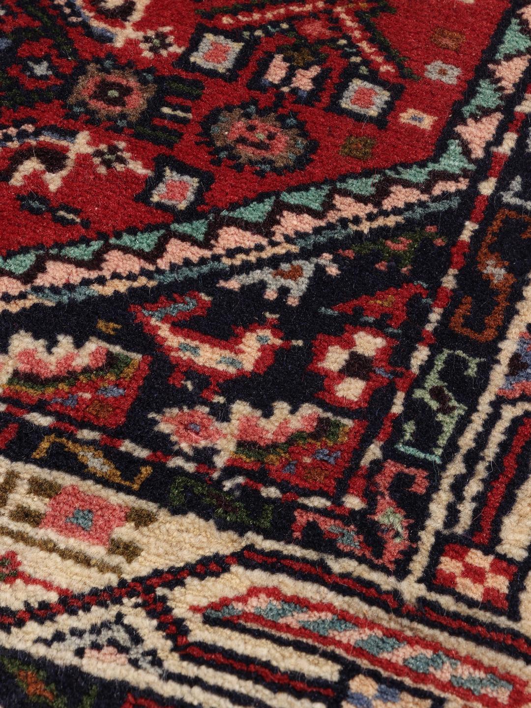 A hand-knotted Hamadan rug from the Middle East featuring a vibrant red and dark blue geometric pattern.