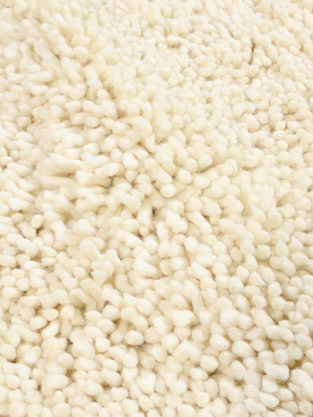 A plush off-white wool rug with a deep pile texture.