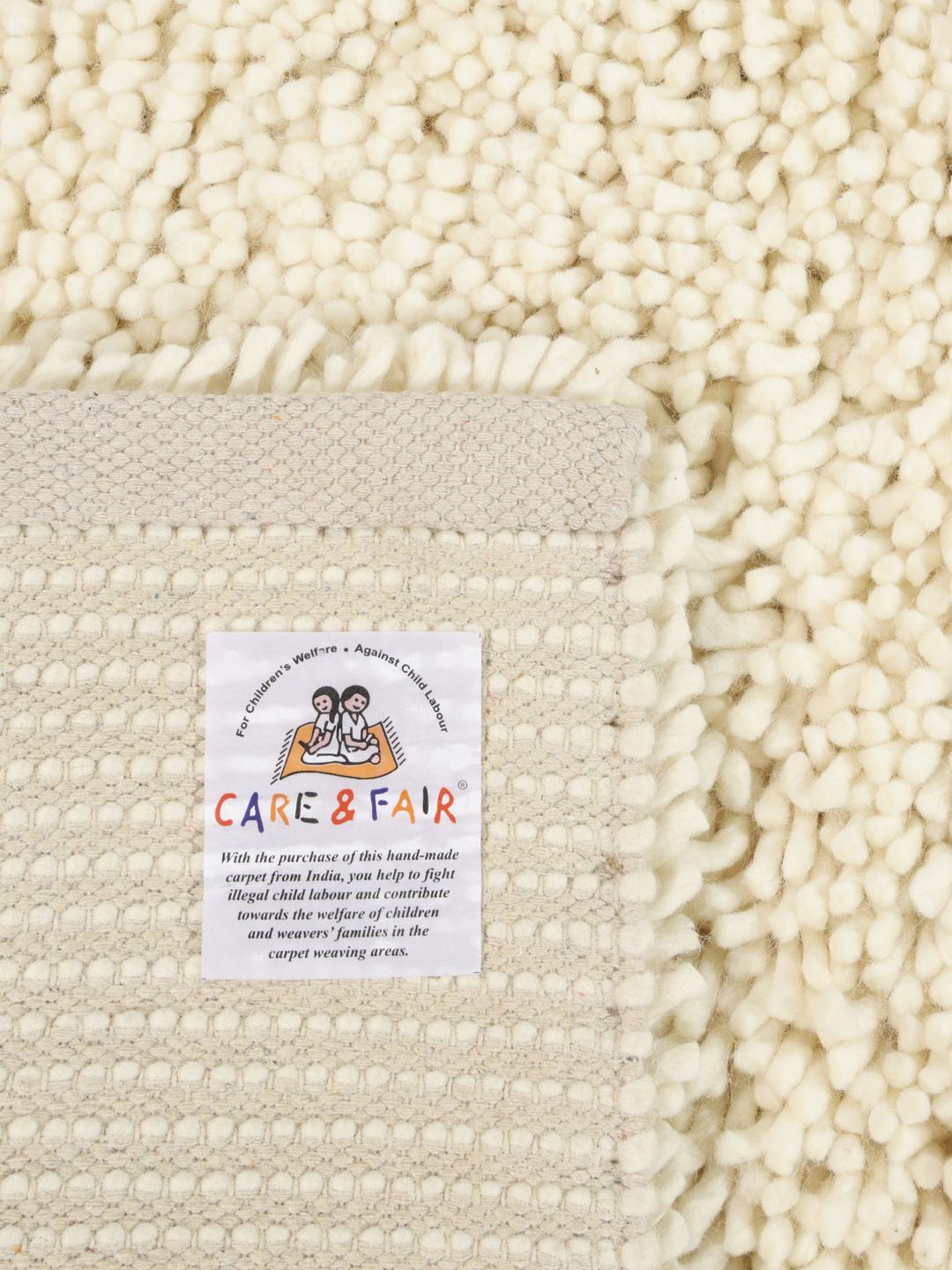 A plush off-white wool rug with a deep pile texture.