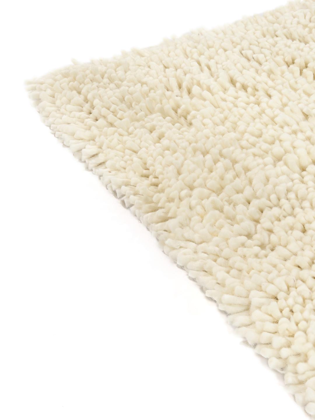 Un tapis en laine blanc cassé très moelleux avec une texture à poils longs.