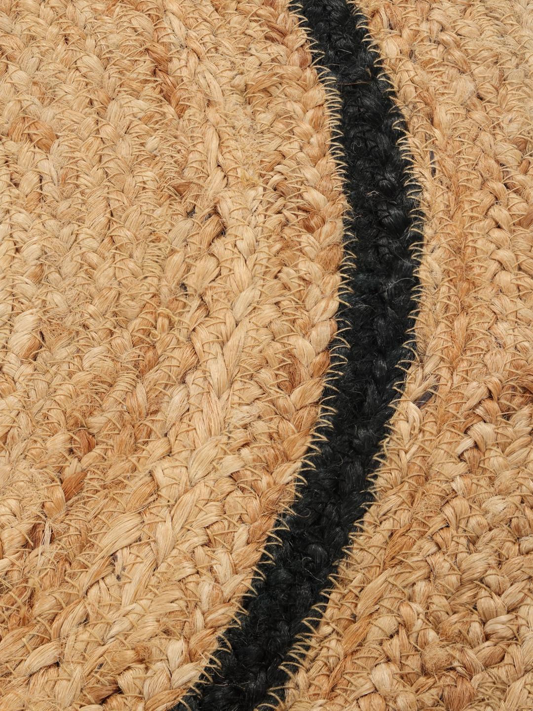 Een bloemvormig beige jute vloerkleed met een zwarte rand.