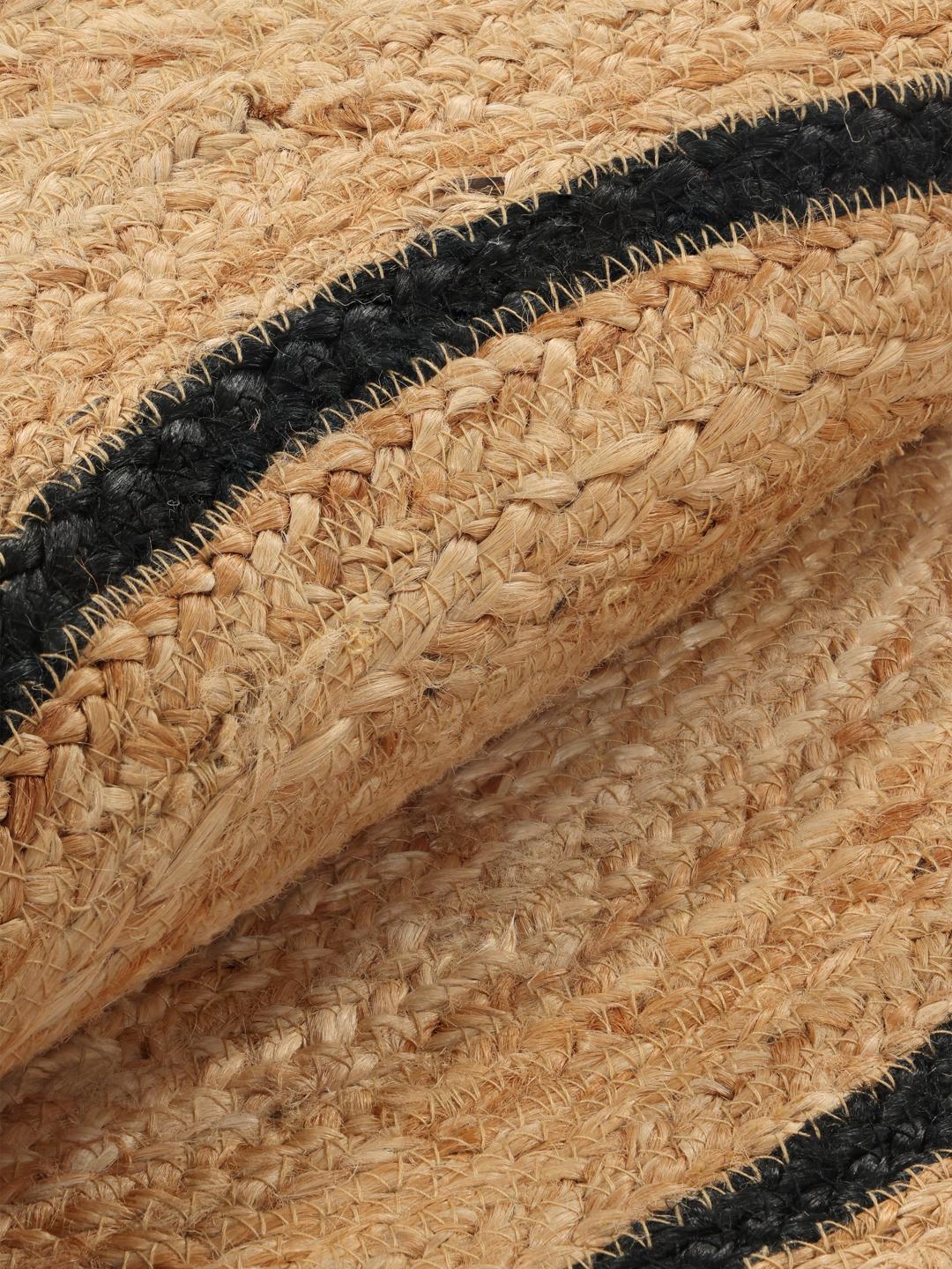 Een bloemvormig beige jute vloerkleed met een zwarte rand.