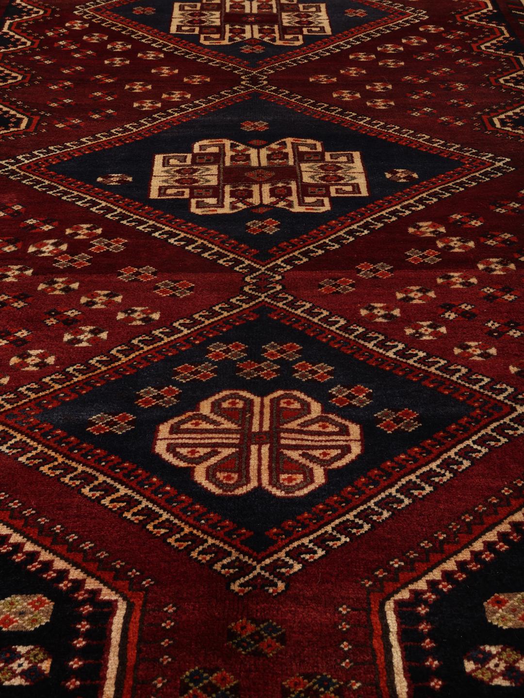 Handgeknoopt tapijt uit het Midden-Oosten in donkerrood met traditionele geometrische motieven