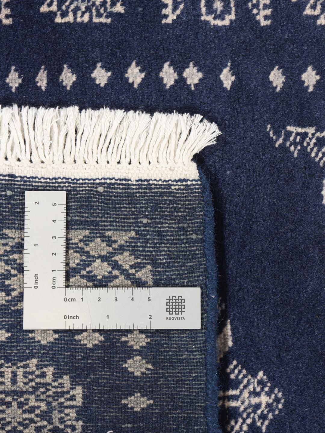 Hand-knotted wool rug from Pakistan in dark-blue with light-coloured geometric motifs.