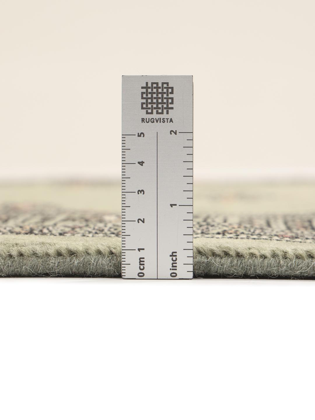 A long, hand-knotted Pakistan Bokhara runner rug in a soft sage green colour with repeating geometric motifs.