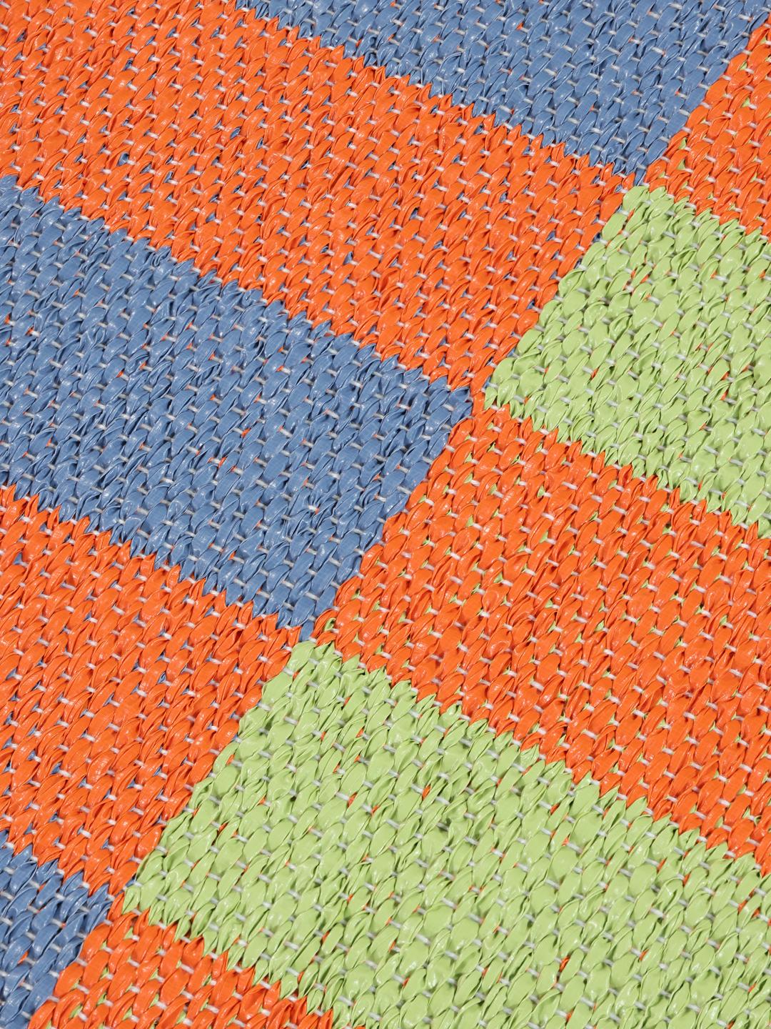 Un tapis rectangulaire présentant un motif à carreaux vibrant orange bleu et vert clair.
