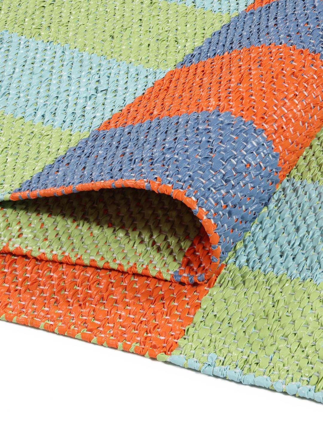 Un tapis rectangulaire présentant un motif à carreaux vibrant orange bleu et vert clair.
