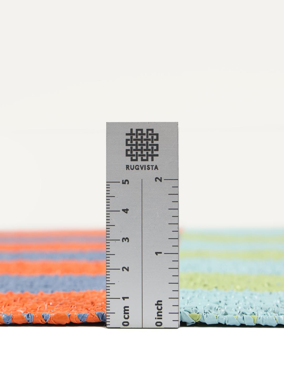 Un tapis rectangulaire présentant un motif à carreaux vibrant orange bleu et vert clair.