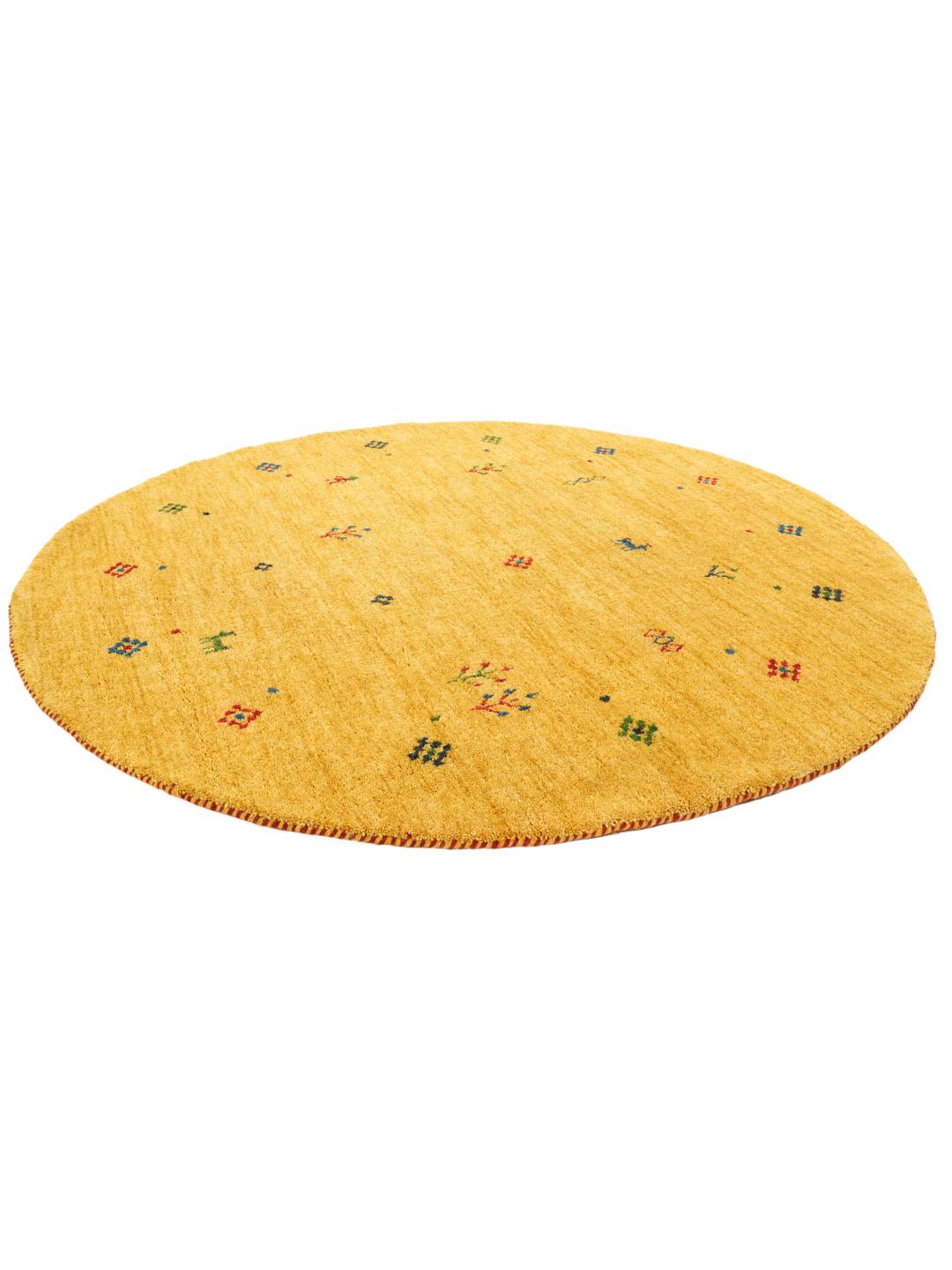 Rond geel tapijt met kleine kleurrijke motieven op een houten vloer