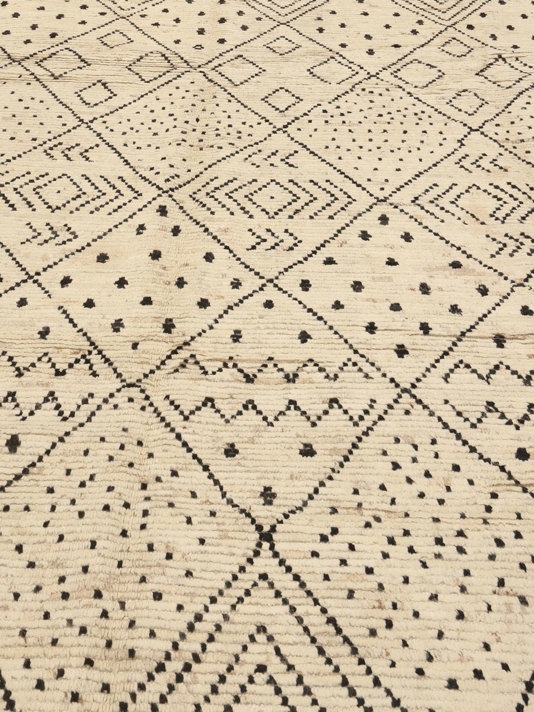 Et stort rektangulært tæppe fra Afghanistan med en beige baggrund og sorte geometriske diamantmønstre.