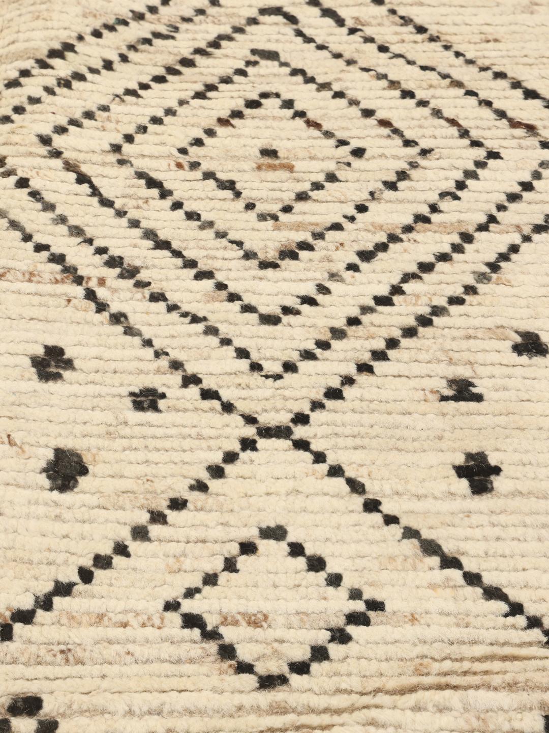 Et stort rektangulært tæppe fra Afghanistan med en beige baggrund og sorte geometriske diamantmønstre.