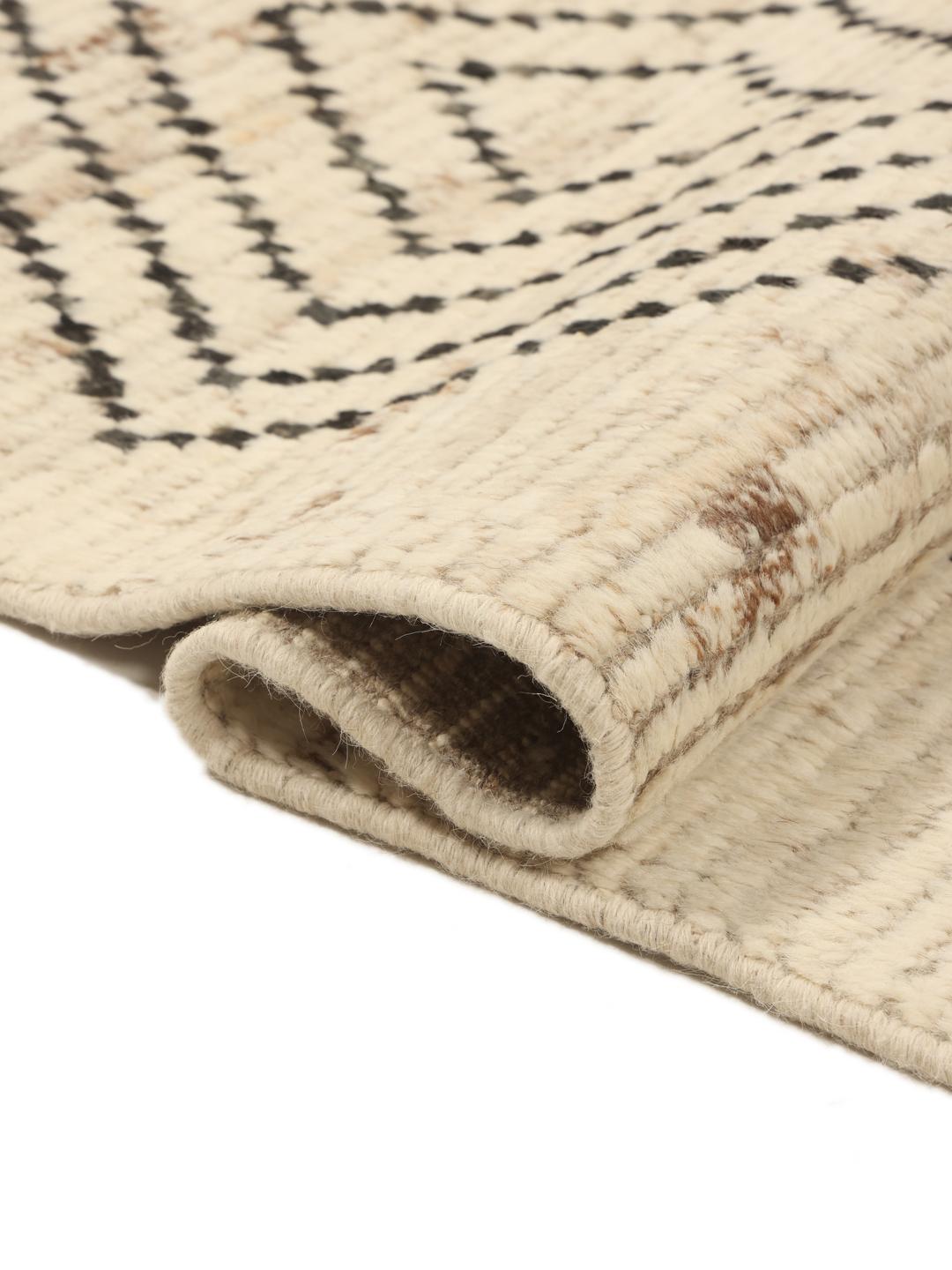 Et stort rektangulært tæppe fra Afghanistan med en beige baggrund og sorte geometriske diamantmønstre.