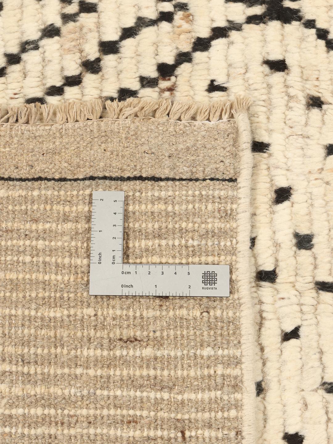 Et stort rektangulært tæppe fra Afghanistan med en beige baggrund og sorte geometriske diamantmønstre.