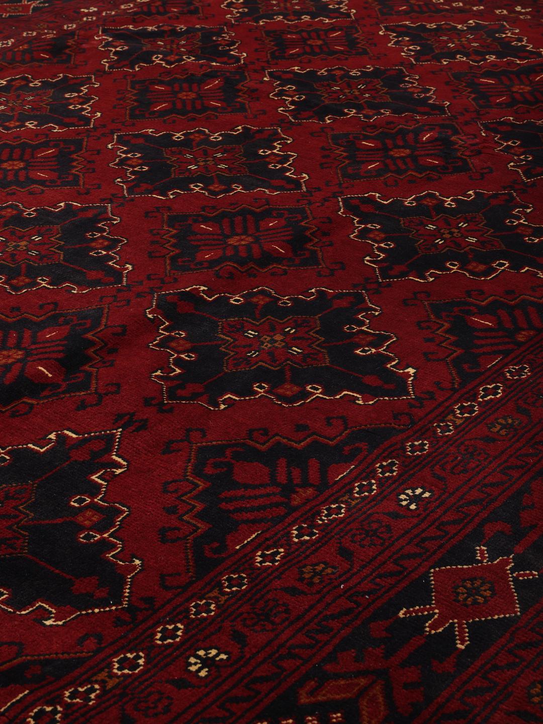 A hand-knotted Kunduz rug from Afghanistan with a dark-red field and geometric patterns.