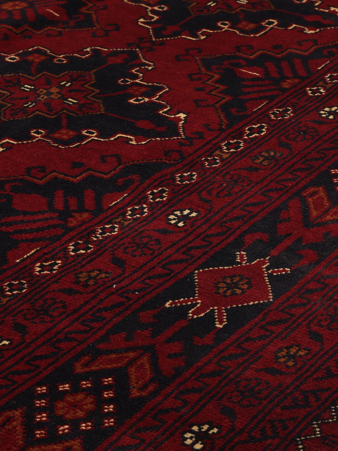 A hand-knotted Kunduz rug from Afghanistan with a dark-red field and geometric patterns.