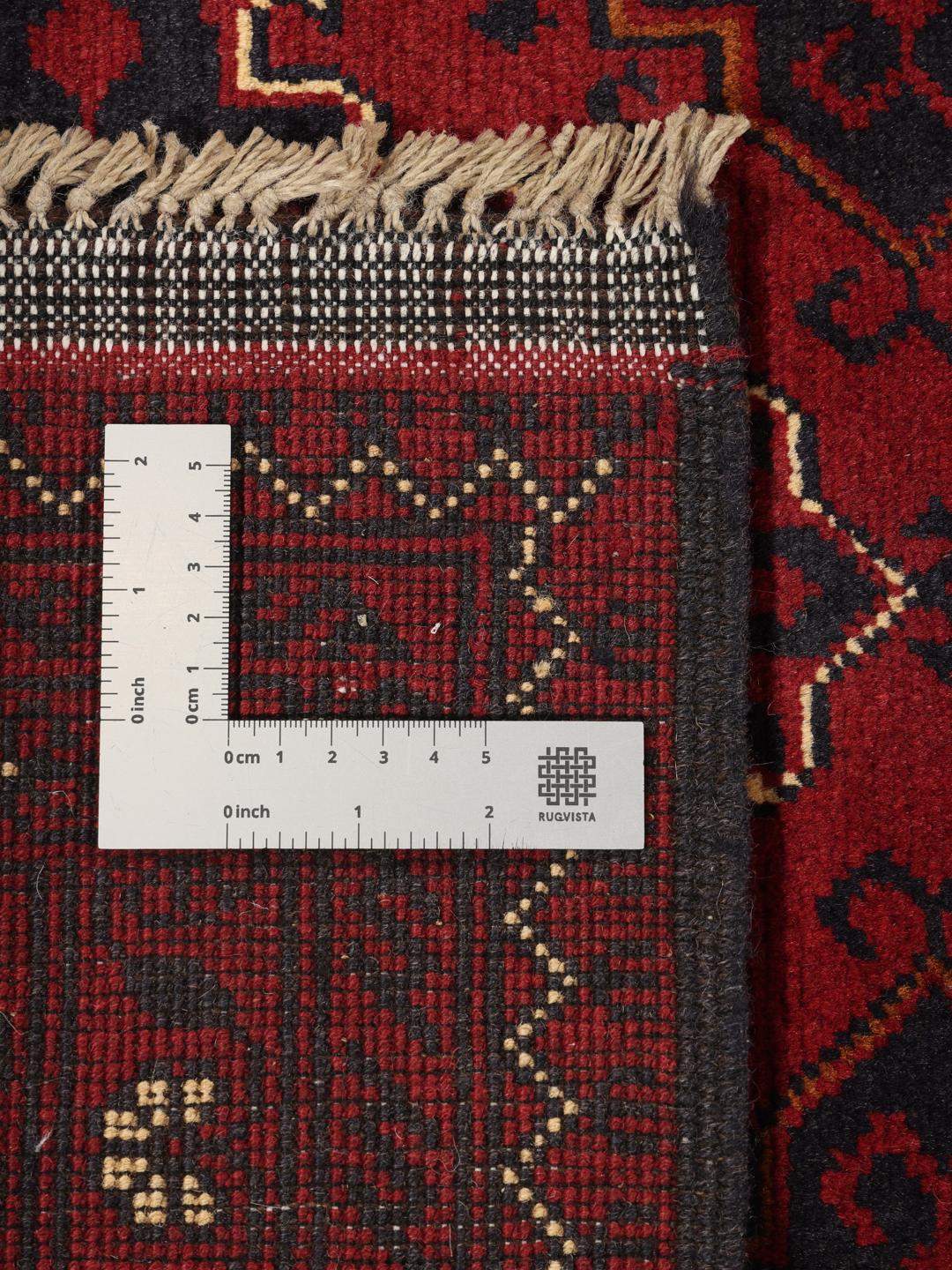 A hand-knotted Kunduz rug from Afghanistan with a dark-red field and geometric patterns.