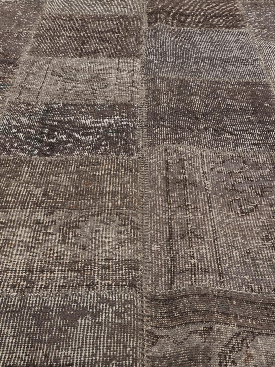 Et rektangulært patchwork-teppe fra Tyrkia i mørkegrå og svarte toner.