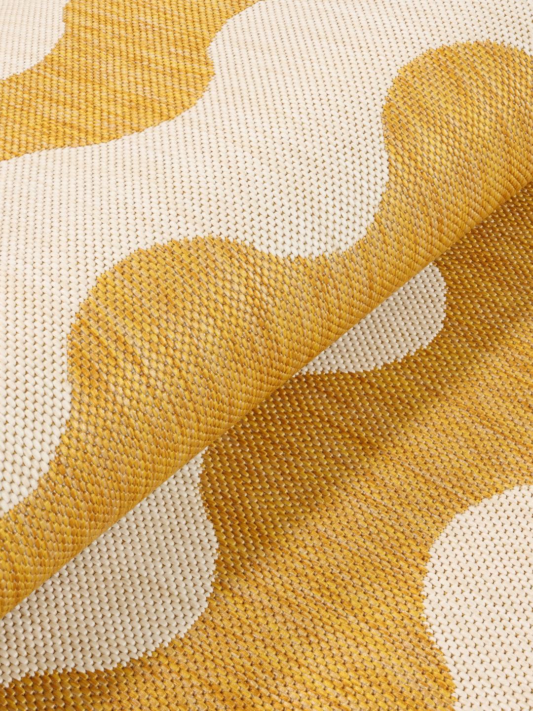Un tapis rond jaune et blanc avec un motif ondulé