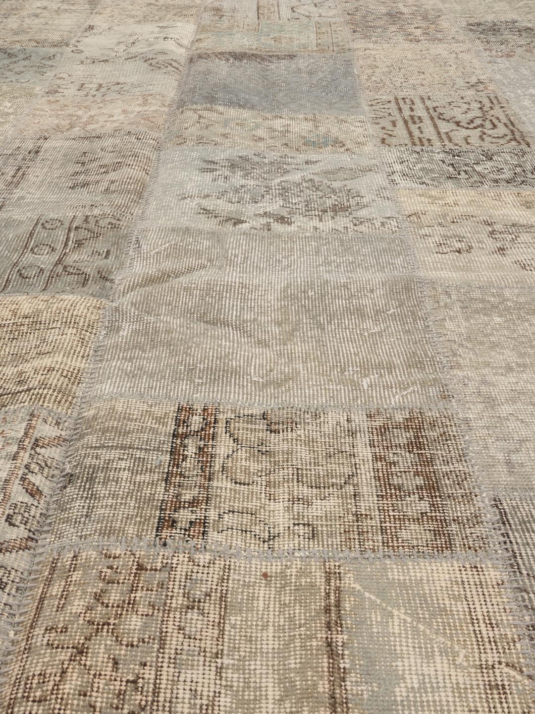 Een uniek patchwork tapijt uit het Midden-Oosten met een neutraal kleurenpalet van beige en grijstinten.