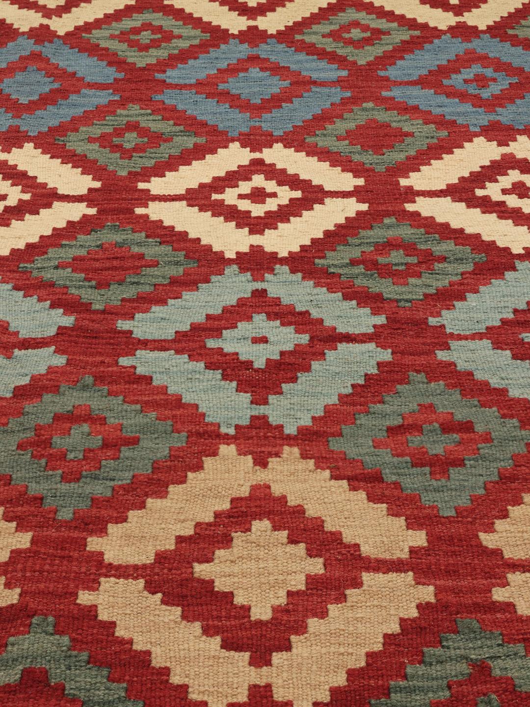 Een handgeweven Kelim Ghashghai tapijt uit het Midden-Oosten in rode, blauwe en beige geometrische patronen.