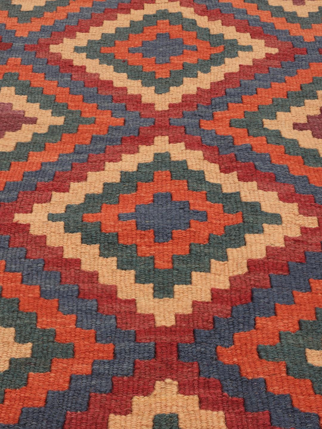 Handgeweven Kelim Ghashghai tapijt met een levendig geometrisch patroon in rood-, blauw- en oranjetinten.