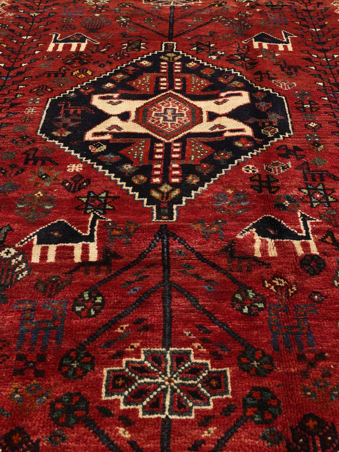 Hand-woven Shiraz rug from the Middle East featuring a vibrant red and black palette with tribal motifs