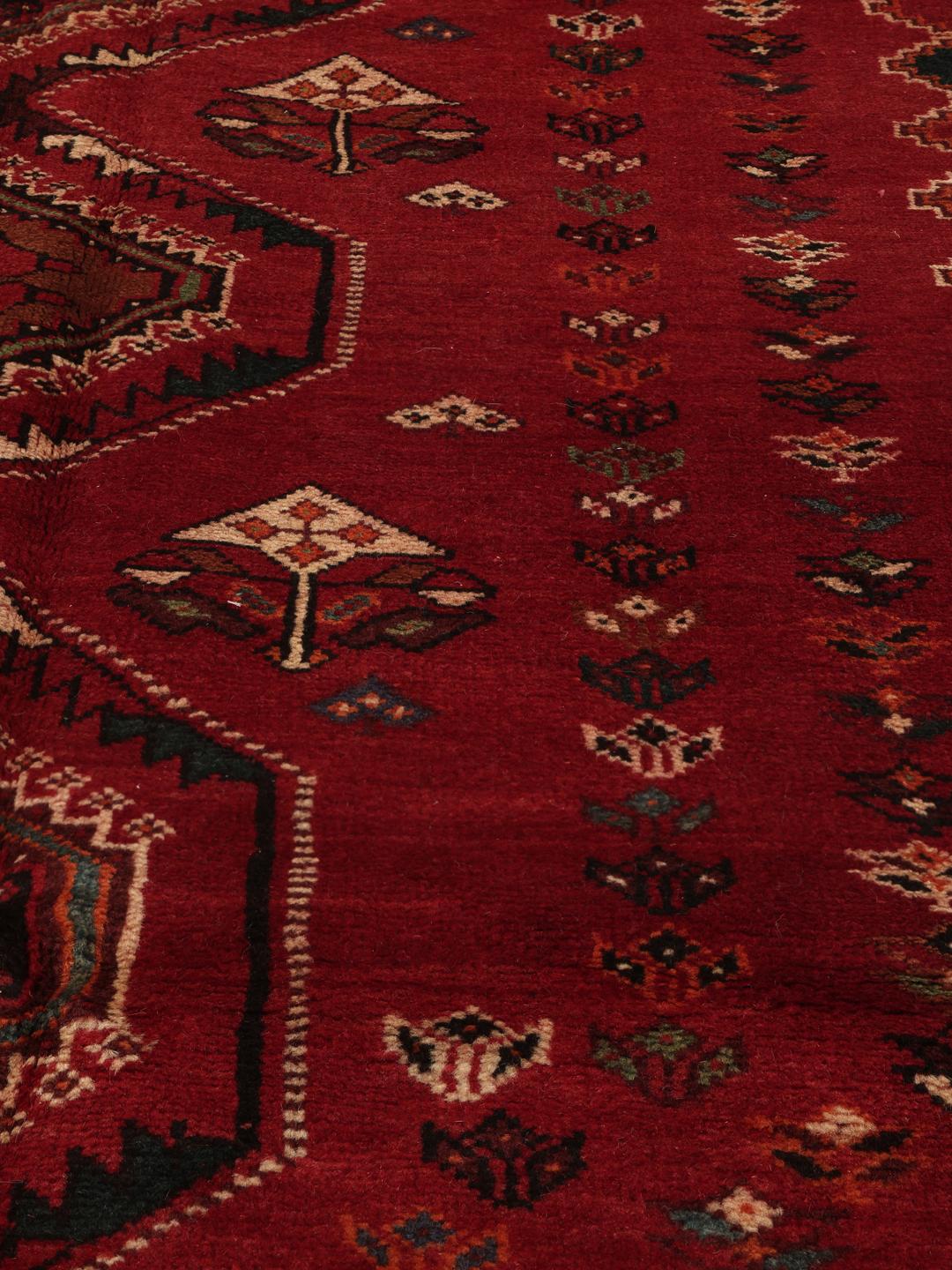 Hand-woven Shiraz rug from the Middle East featuring a vibrant red field and tribal motifs