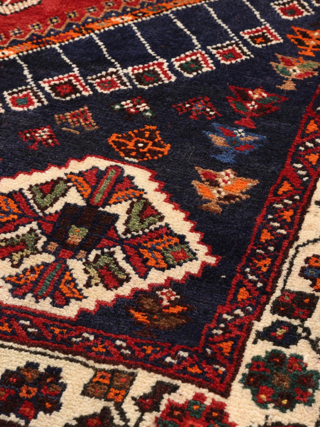 Hand-knotted Qashqai rug with a red field and geometric tribal patterns