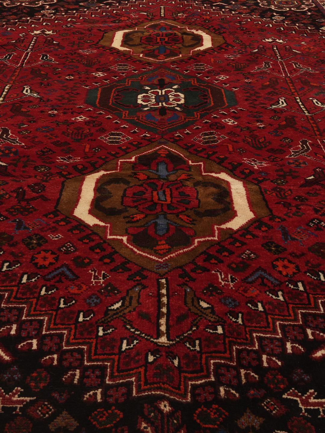 Hand-woven Shiraz rug from the Middle East featuring a red and black tribal pattern.