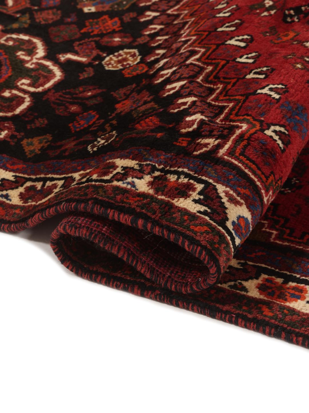 Hand-woven Shiraz rug from the Middle East featuring a red and black tribal pattern.