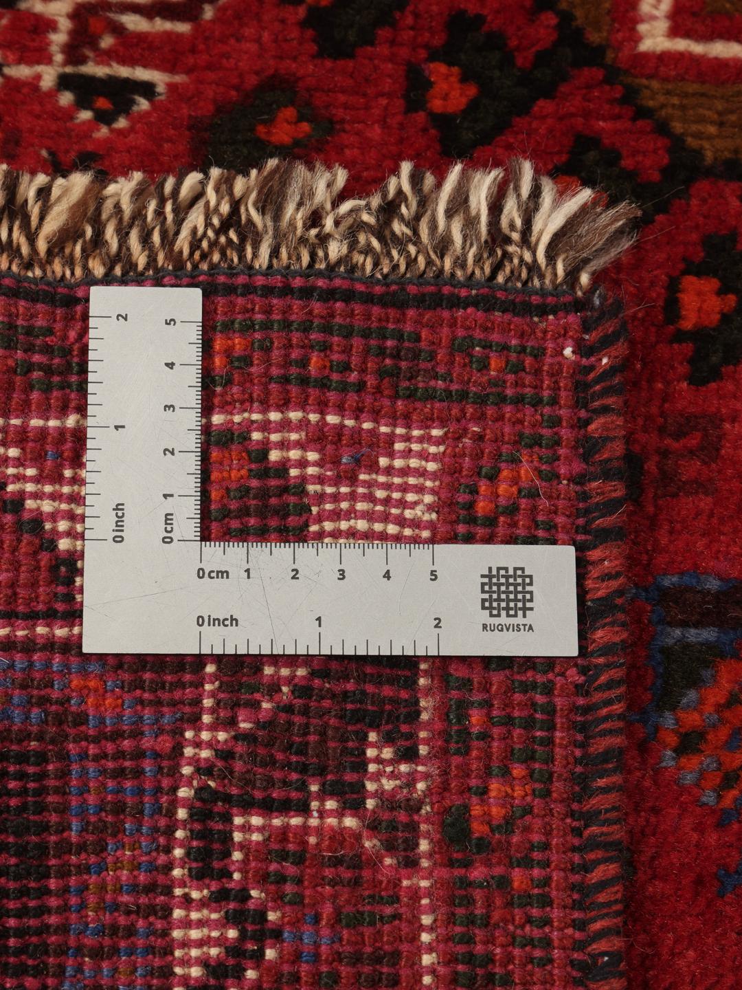 Hand-woven Shiraz rug from the Middle East featuring a red and black tribal pattern.