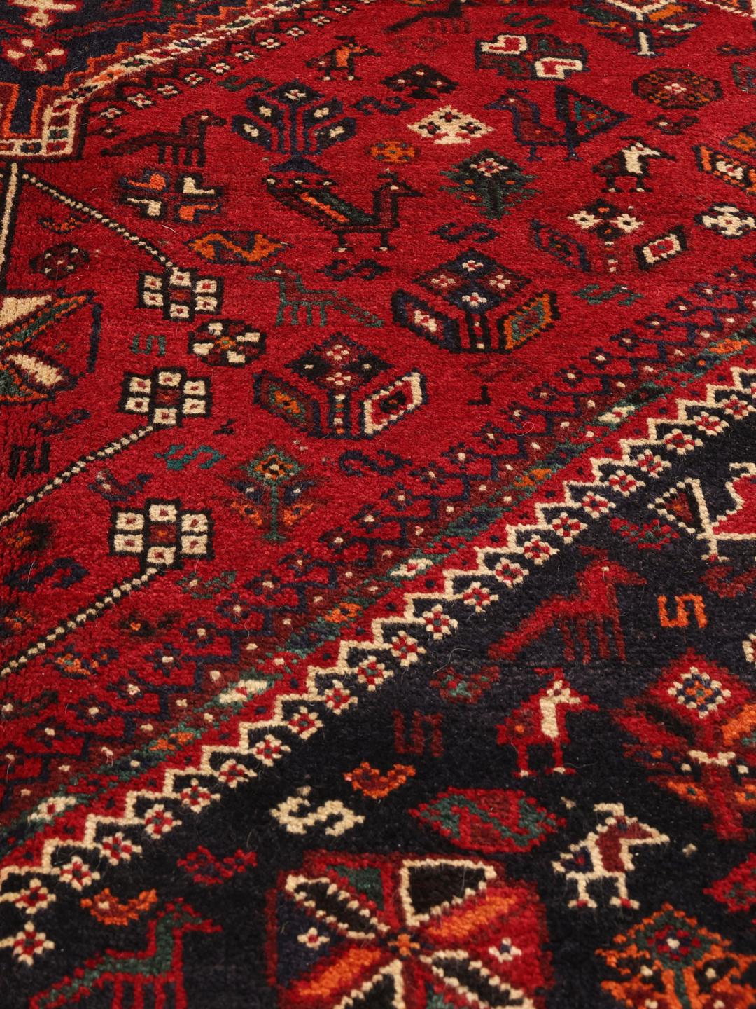 Hand-knotted Middle Eastern tribal rug with red and black geometric patterns