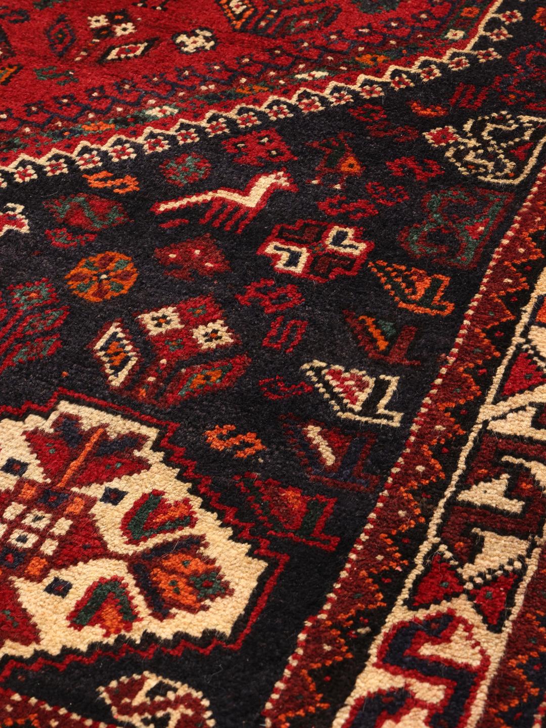 Hand-knotted Middle Eastern tribal rug with red and black geometric patterns