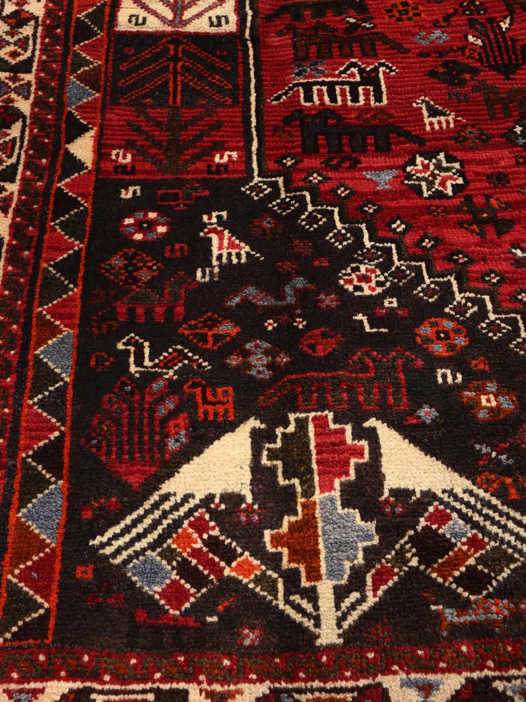 A beautiful hand-knotted Qashqai rug from the Middle East with a red field and traditional patterns.
