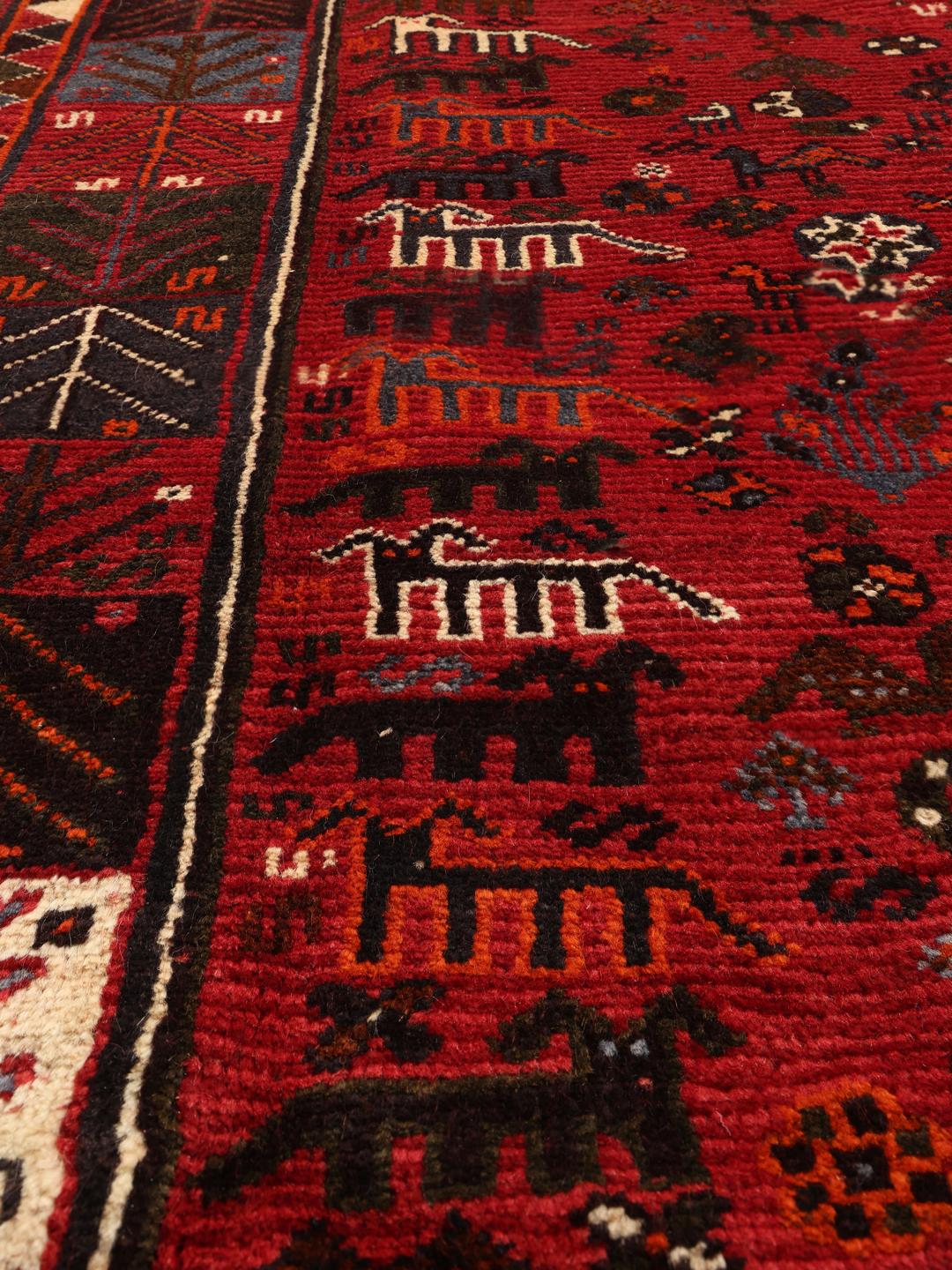 A beautiful hand-knotted Qashqai rug from the Middle East with a red field and traditional patterns.