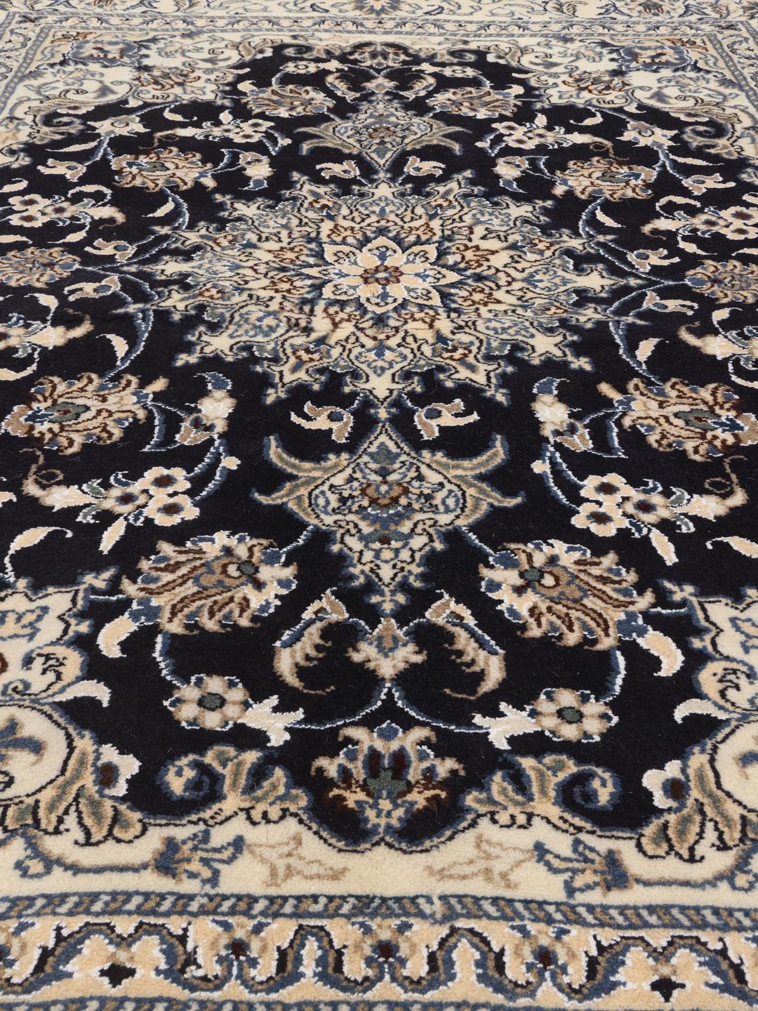 A hand-knotted Nain rug from the Middle East featuring a blue and beige floral design.