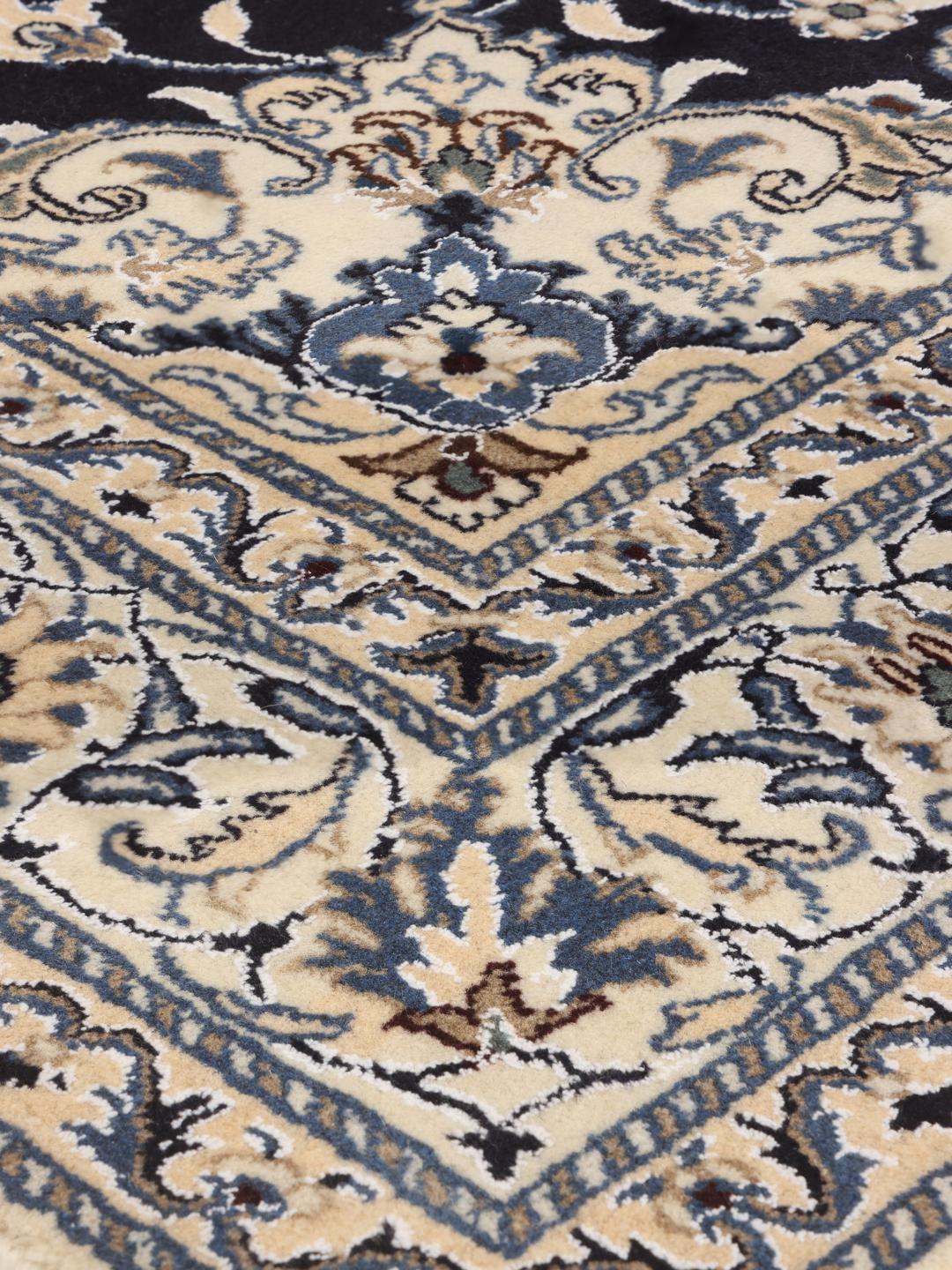 A hand-knotted Nain rug from the Middle East featuring a blue and beige floral design.