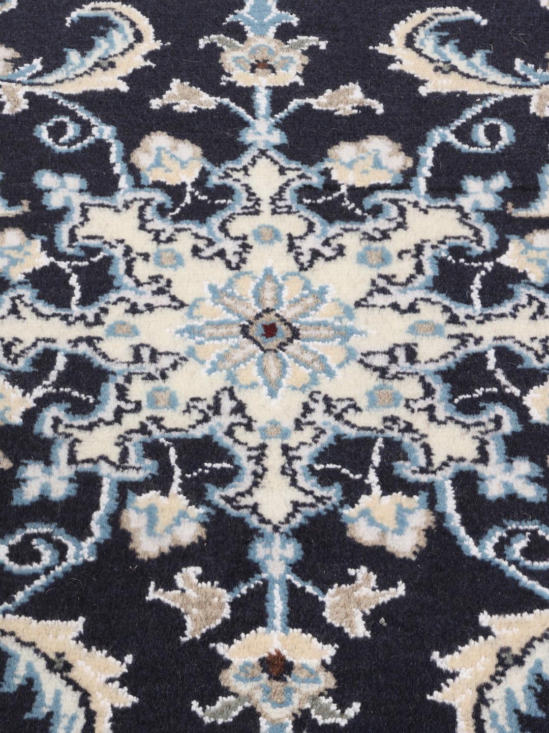 A hand-knotted Nain rug from the Middle East with a deep blue field and floral motifs.