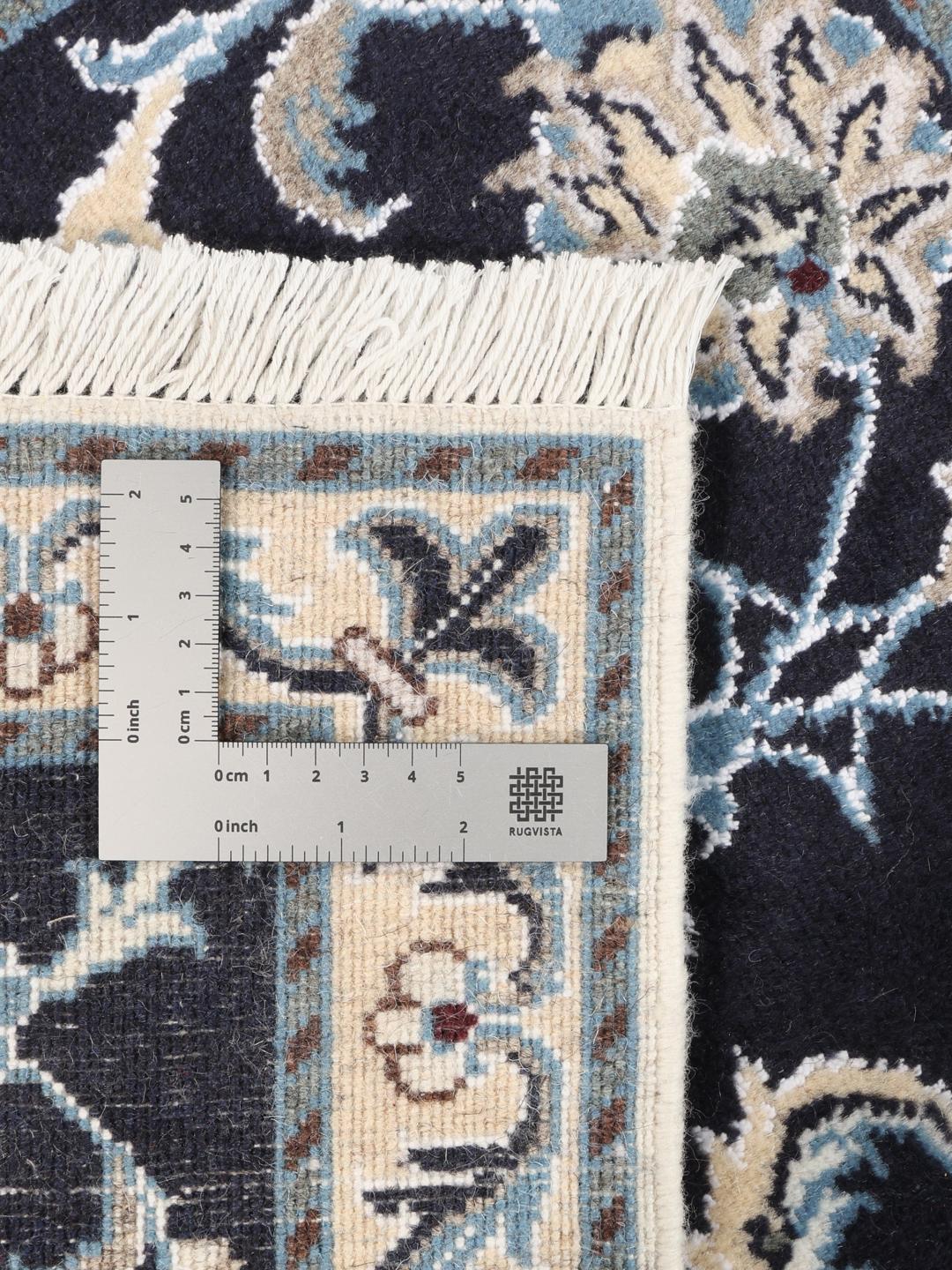 A hand-knotted Nain rug from the Middle East with a deep blue field and floral motifs.