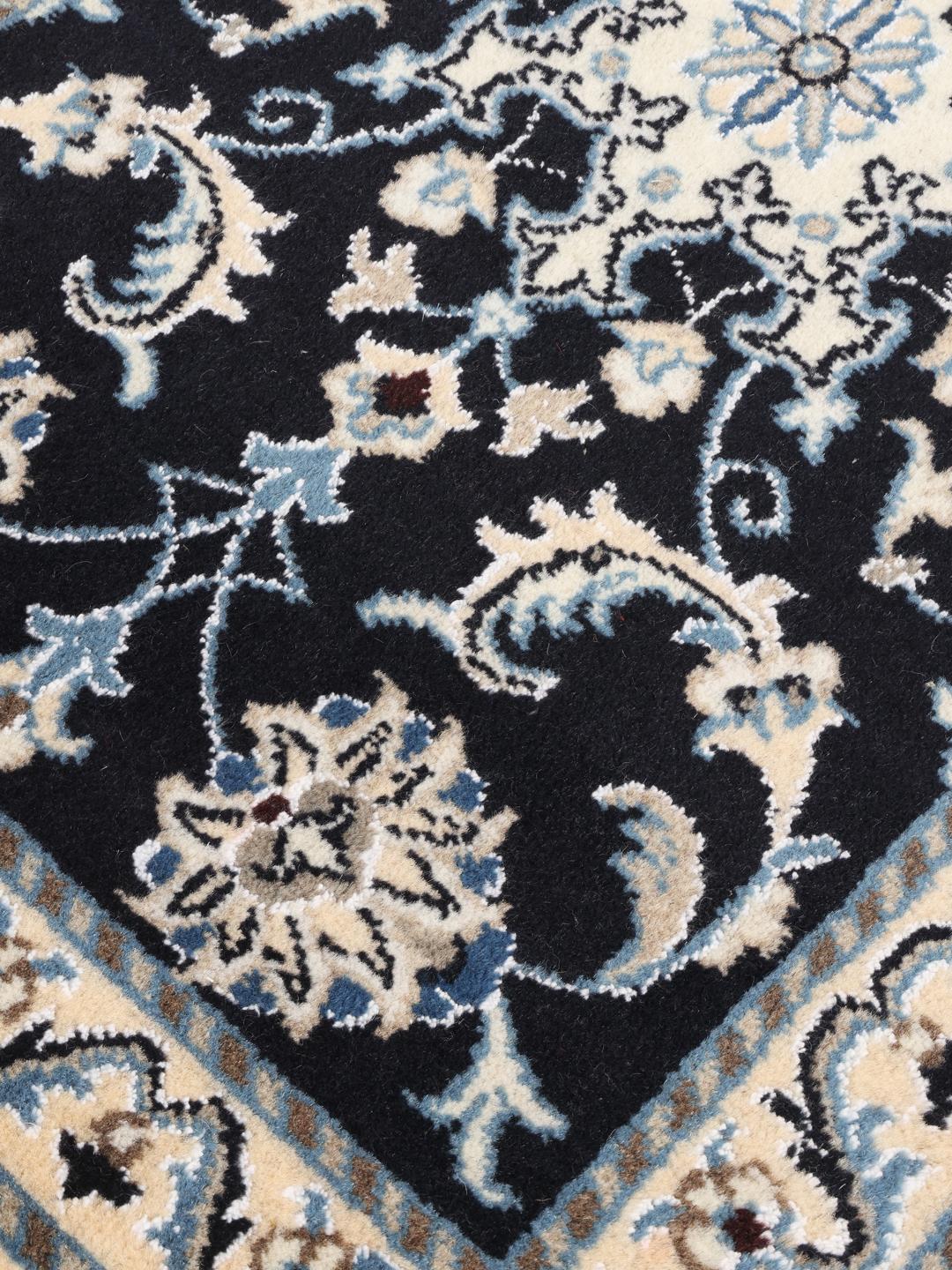 A hand-knotted Nain rug from the Middle East featuring a black field with floral patterns