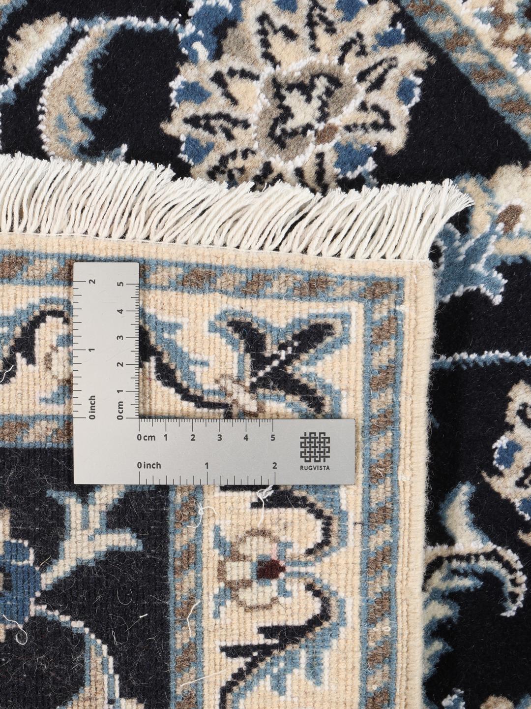 A hand-knotted Nain rug from the Middle East featuring a black field with floral patterns