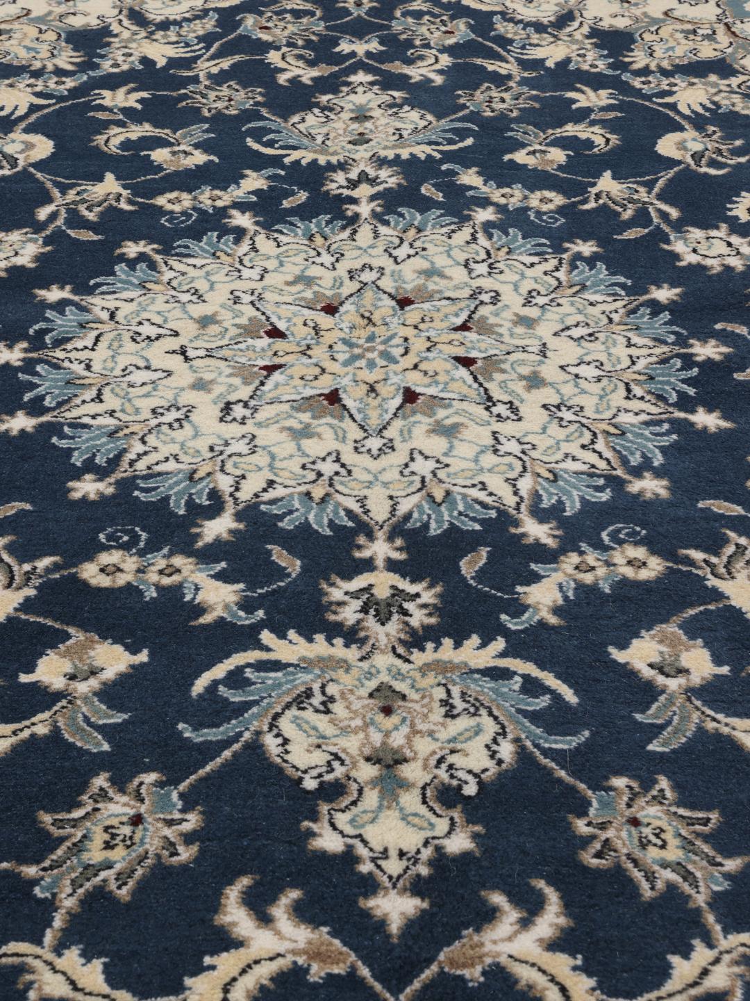 Hand-knotted Nain rug from the Middle East featuring a blue field with floral patterns.