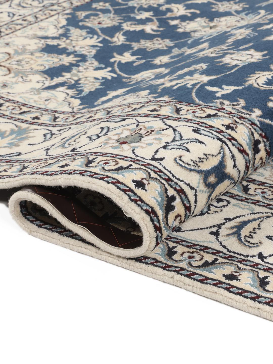 Hand-knotted Nain rug from the Middle East featuring a blue field with floral patterns.